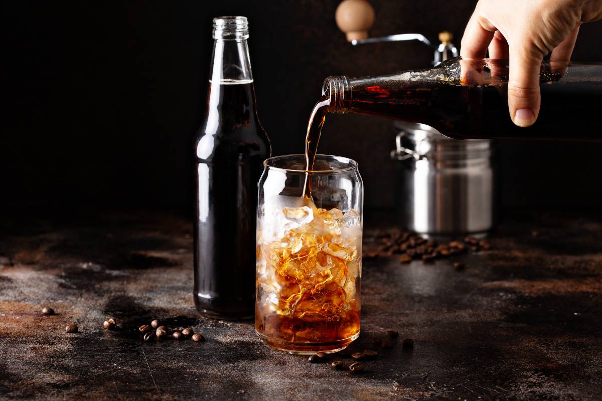 Cold brew iced coffee in glass bottles being poured over ice