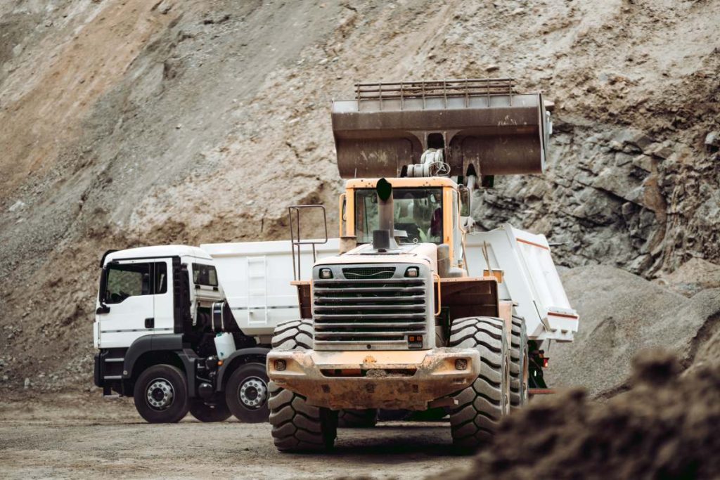 Industrial dumper trucks and wheel loader working on construction site, loading and unloading gravel and earth. heavy duty machinery activity