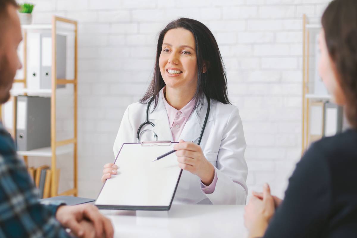Smiling Woman Doctor Discussing Medical Information With Couple in works health Office