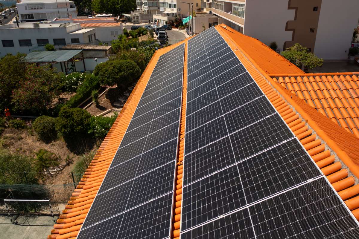 From above of solar panels on house rooftop in city. The residential structure is equipped with green renewable energy generators.
